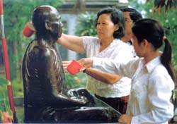 Buddhist devotees pour water over the statue